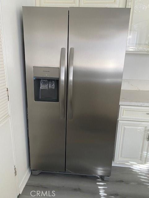 room details featuring stainless steel fridge and concrete flooring