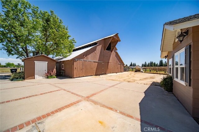 view of home's exterior with a patio area and a storage shed