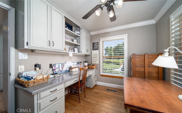 office area featuring built in desk, light hardwood / wood-style flooring, ceiling fan, and ornamental molding