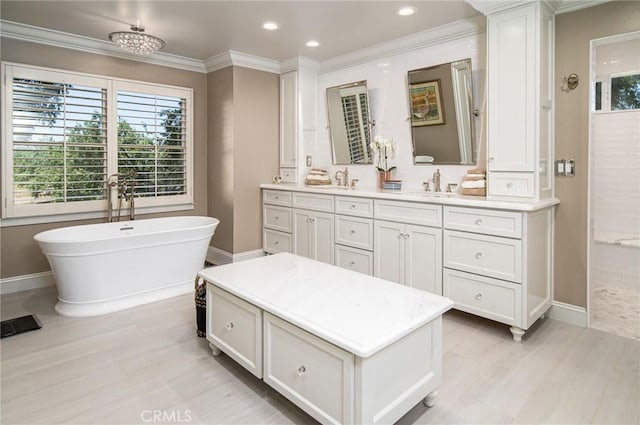 bathroom with a tub to relax in, vanity, and ornamental molding