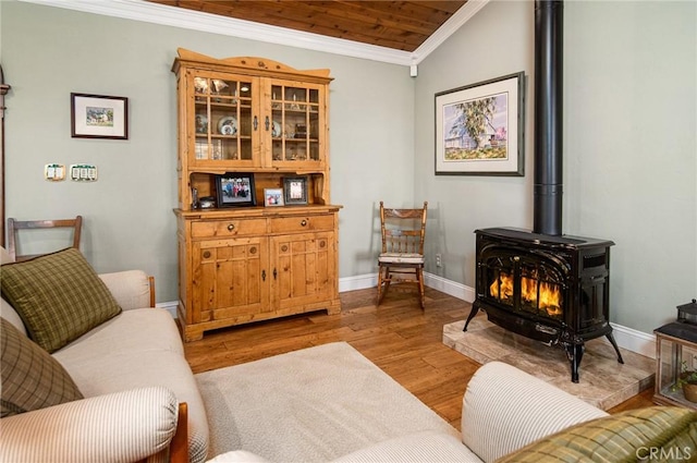 living area featuring ornamental molding, light hardwood / wood-style flooring, a wood stove, and lofted ceiling