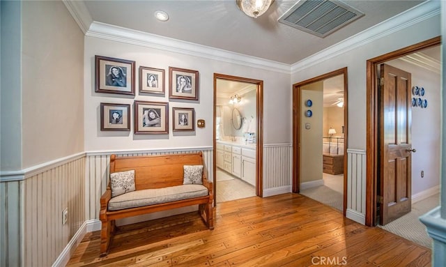 living area with crown molding and light hardwood / wood-style flooring