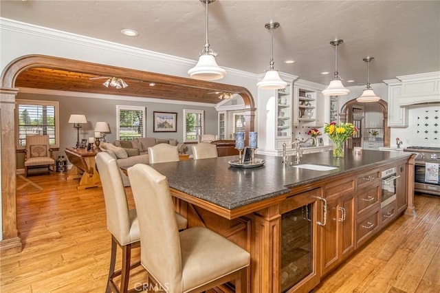 kitchen with sink, hanging light fixtures, an island with sink, a breakfast bar area, and appliances with stainless steel finishes