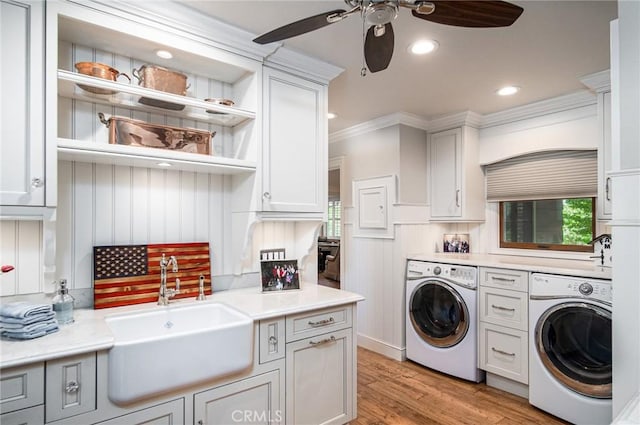 washroom featuring ceiling fan, sink, cabinets, washer and dryer, and light wood-type flooring