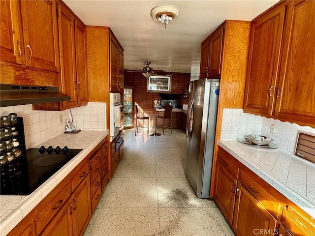 kitchen with backsplash, stainless steel refrigerator, white oven, and black electric cooktop