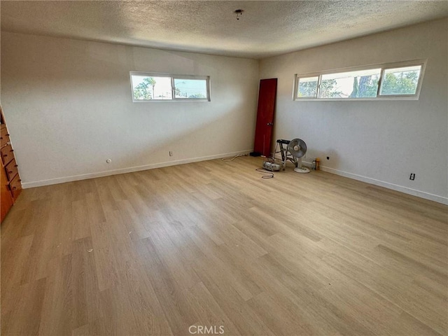 spare room featuring a wealth of natural light, light hardwood / wood-style flooring, and a textured ceiling