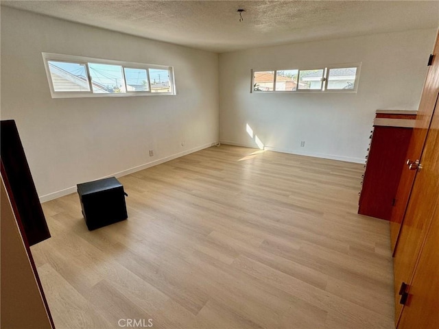 empty room featuring a textured ceiling and light hardwood / wood-style flooring