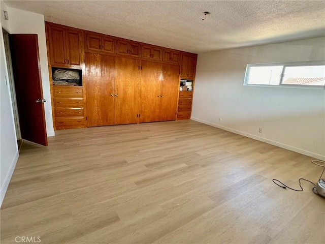 unfurnished bedroom with a textured ceiling, light hardwood / wood-style floors, and a closet