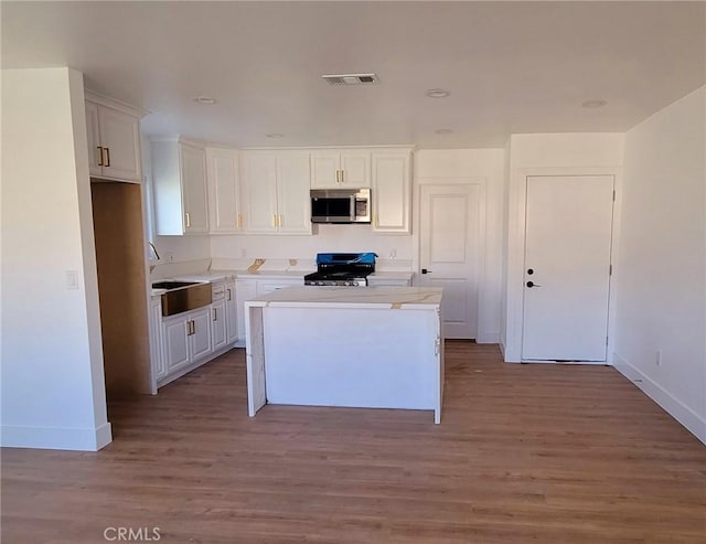 kitchen featuring sink, black gas range oven, white cabinetry, and a center island