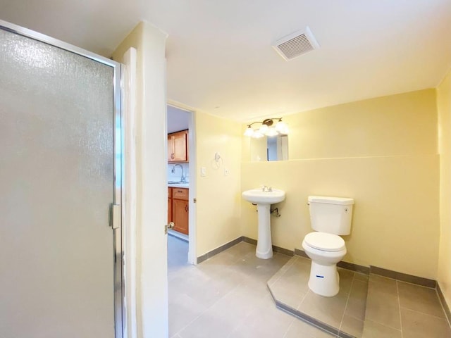 bathroom featuring an enclosed shower, sink, tile patterned floors, and toilet