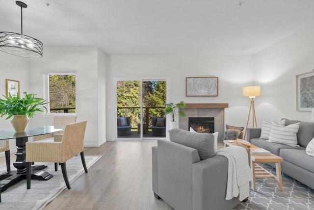 living room with a tiled fireplace, an inviting chandelier, and light hardwood / wood-style floors