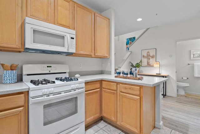 kitchen with light tile patterned floors, light brown cabinetry, white appliances, and kitchen peninsula