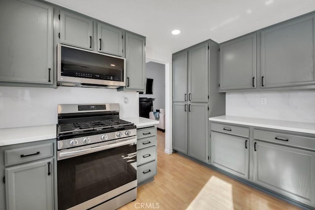 kitchen with stainless steel appliances, gray cabinetry, and light hardwood / wood-style floors