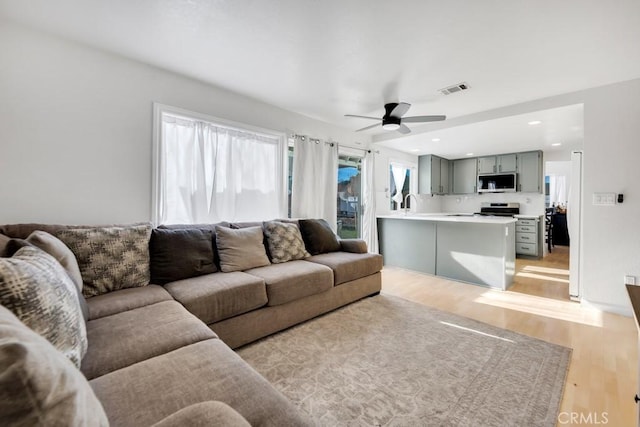 living room with ceiling fan, light hardwood / wood-style floors, and sink