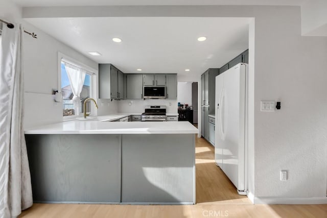 kitchen featuring light hardwood / wood-style floors, sink, kitchen peninsula, and stainless steel appliances