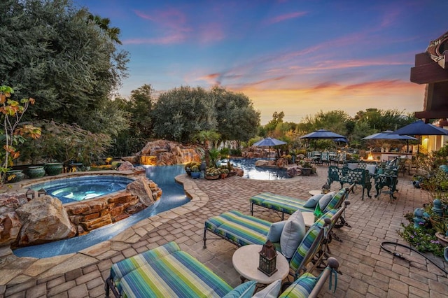 patio terrace at dusk with a pool with hot tub