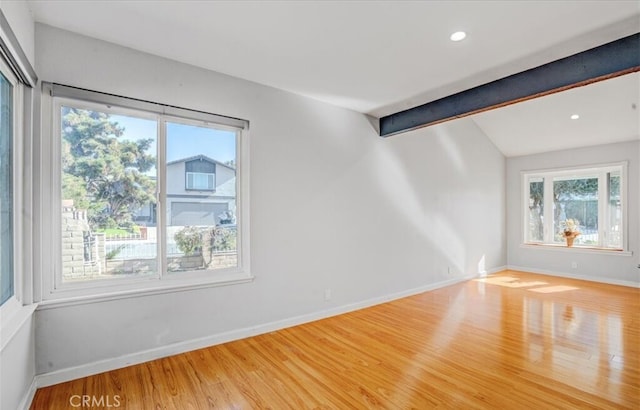 empty room with vaulted ceiling with beams and hardwood / wood-style flooring