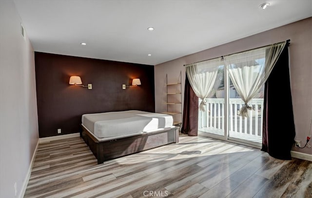 bedroom with access to exterior and hardwood / wood-style flooring