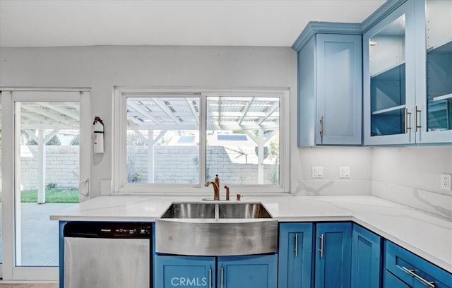 kitchen with dishwasher, light stone counters, blue cabinets, and sink