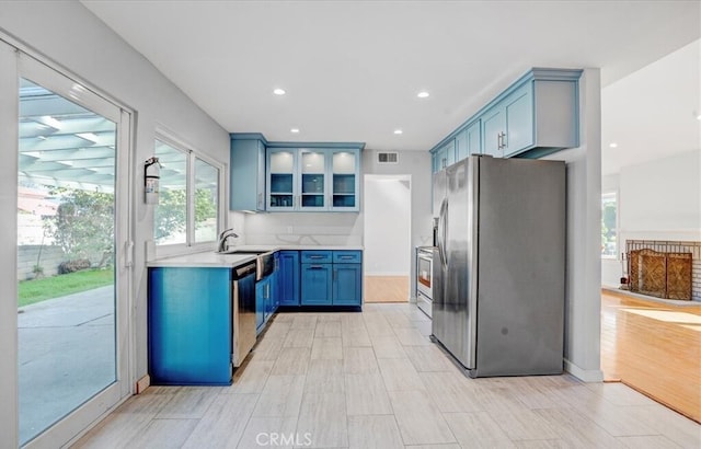 kitchen featuring blue cabinetry, dishwasher, stainless steel refrigerator with ice dispenser, and sink