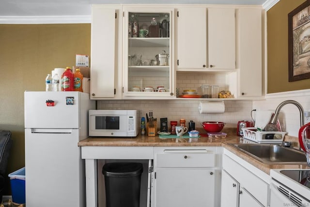 kitchen with tasteful backsplash, ornamental molding, white appliances, sink, and white cabinetry