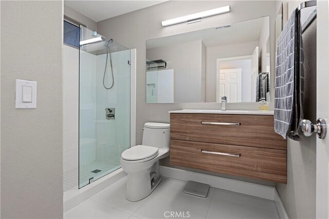 bathroom featuring tile patterned floors, vanity, a tile shower, and toilet