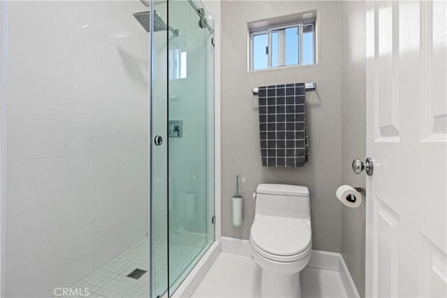 bathroom featuring tile patterned floors, toilet, and a shower with shower door