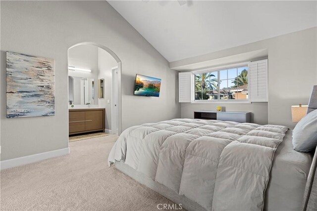 carpeted bedroom with ensuite bathroom and lofted ceiling