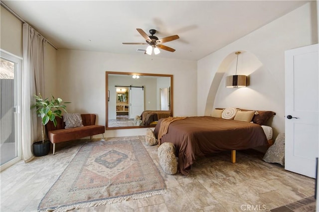 bedroom featuring ceiling fan and a barn door