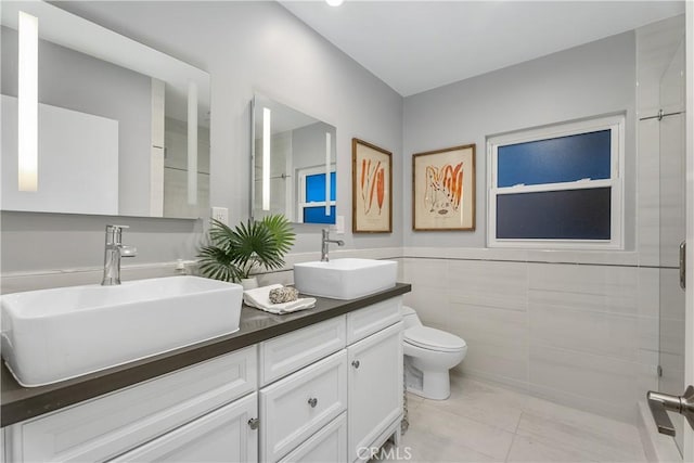 bathroom with vanity, toilet, walk in shower, and tile walls