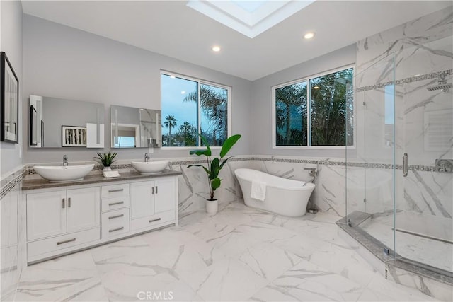 bathroom featuring tile walls, vanity, a skylight, and separate shower and tub