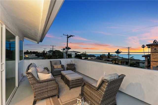 balcony at dusk featuring a water view