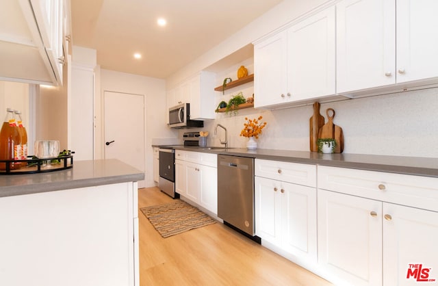 kitchen featuring backsplash, stainless steel appliances, sink, white cabinets, and light hardwood / wood-style floors