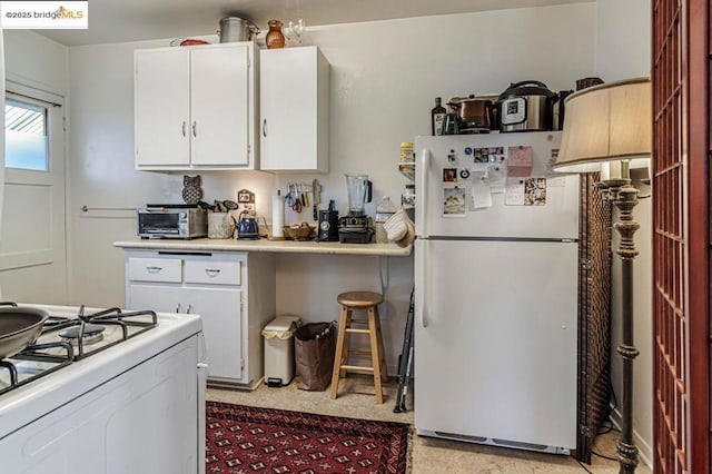 kitchen with white cabinetry and white appliances