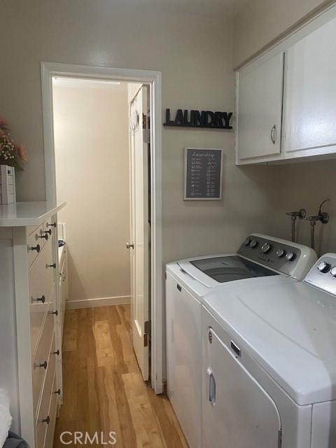 clothes washing area with light wood-style flooring, independent washer and dryer, and cabinet space