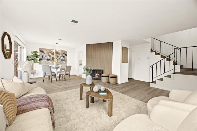 living room featuring a large fireplace, hardwood / wood-style flooring, and a notable chandelier