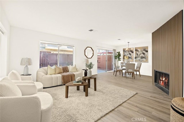 living room featuring light wood-type flooring and a large fireplace