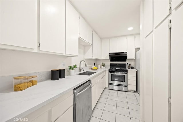 kitchen featuring light tile patterned floors, stainless steel appliances, white cabinetry, and sink