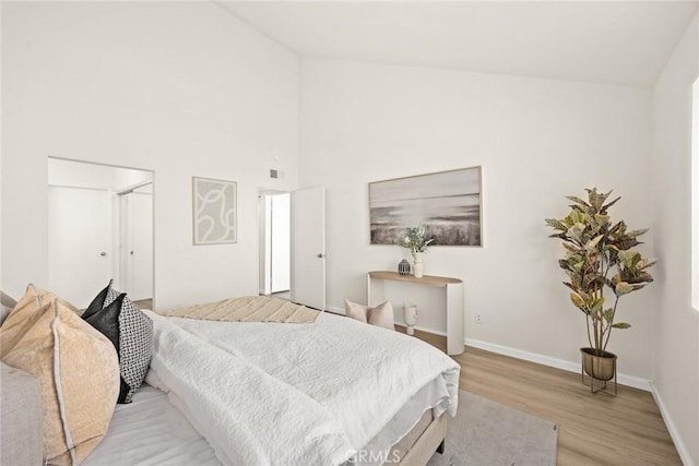 bedroom with high vaulted ceiling and light hardwood / wood-style flooring