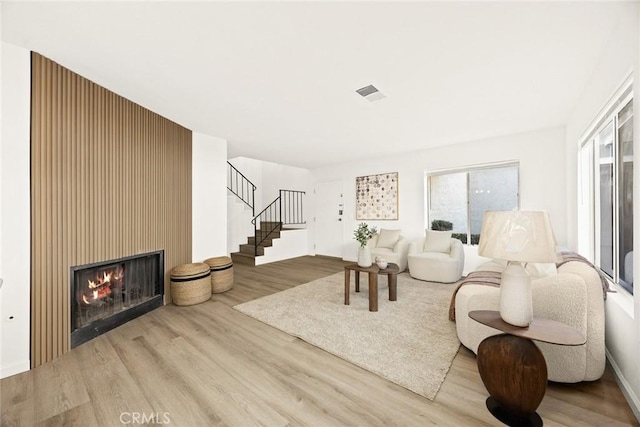 living room featuring light wood-type flooring and a large fireplace