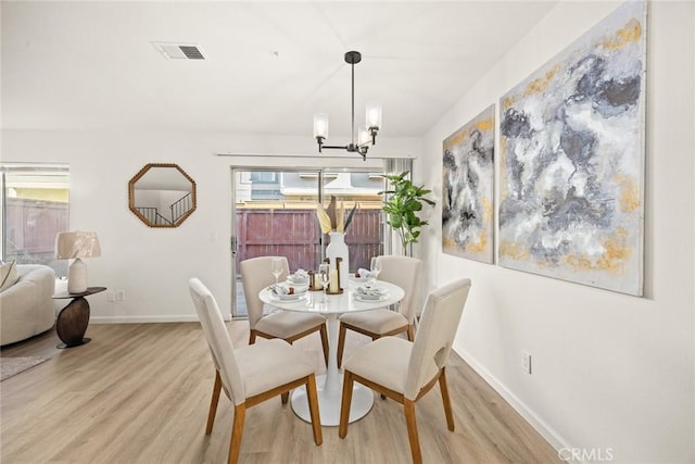 dining area with light wood-type flooring, a wealth of natural light, and a chandelier