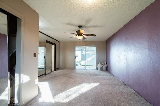 empty room featuring ceiling fan, light colored carpet, and a textured ceiling