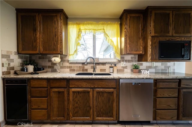 kitchen featuring light stone counters, stainless steel dishwasher, sink, and tasteful backsplash