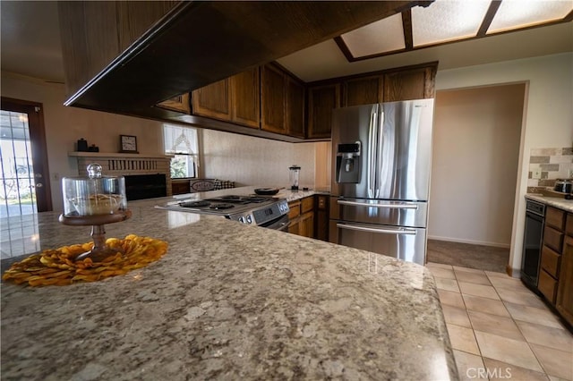 kitchen with stainless steel appliances, light stone countertops, light tile patterned floors, and a fireplace