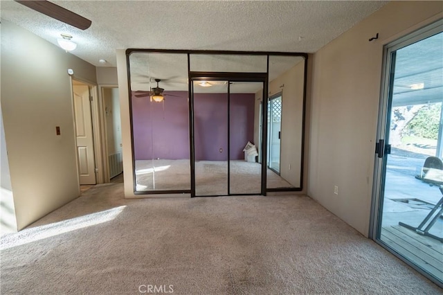 unfurnished bedroom with light carpet, access to exterior, a textured ceiling, and a closet