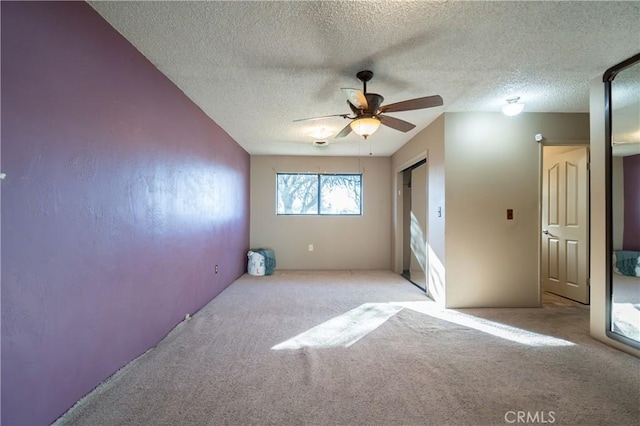 carpeted empty room featuring a textured ceiling and ceiling fan