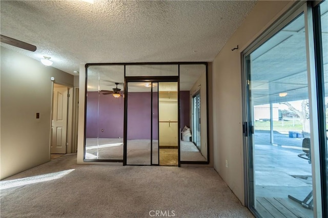 unfurnished bedroom featuring carpet, a textured ceiling, a closet, and access to outside