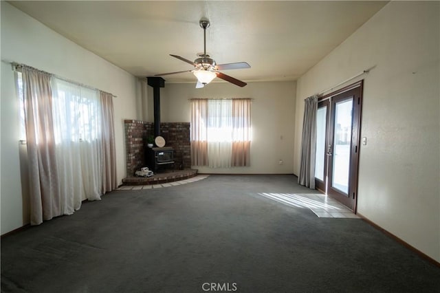 unfurnished living room featuring a healthy amount of sunlight, carpet floors, and a wood stove