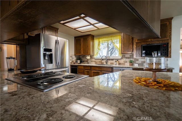 kitchen featuring tasteful backsplash, stainless steel appliances, light stone countertops, and sink