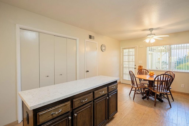 kitchen featuring ceiling fan, dark brown cabinets, and light hardwood / wood-style flooring